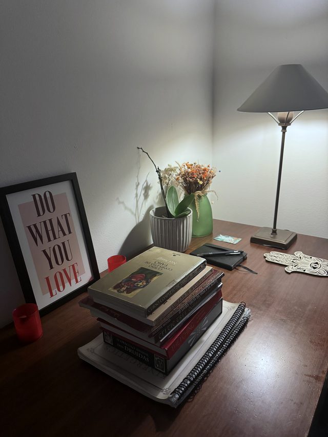 Mesa com livros, flores e luminária no consultório